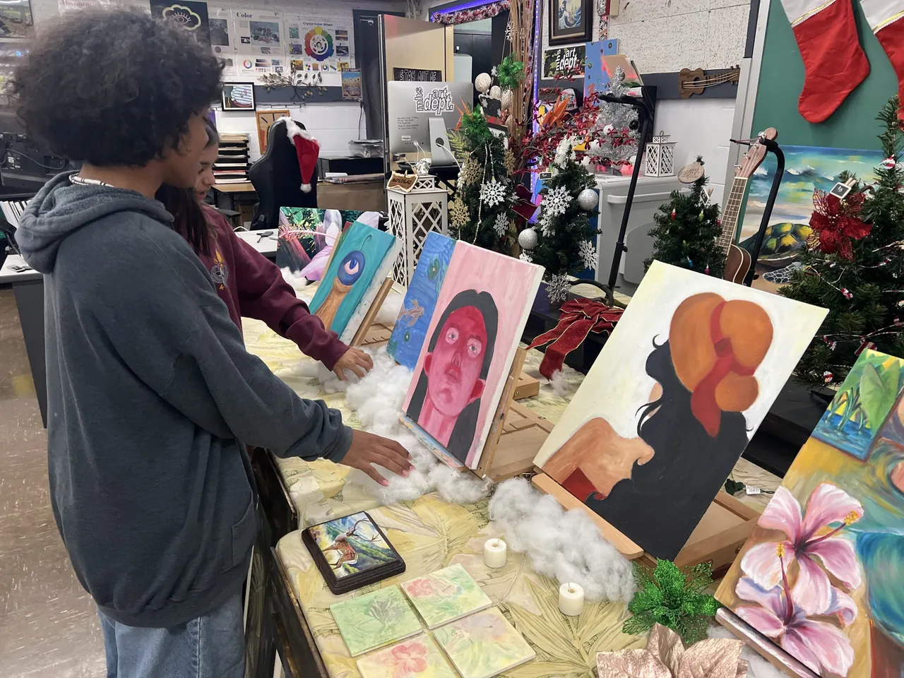 A student looking at paintings displayed at a Molokaʻi High student art show