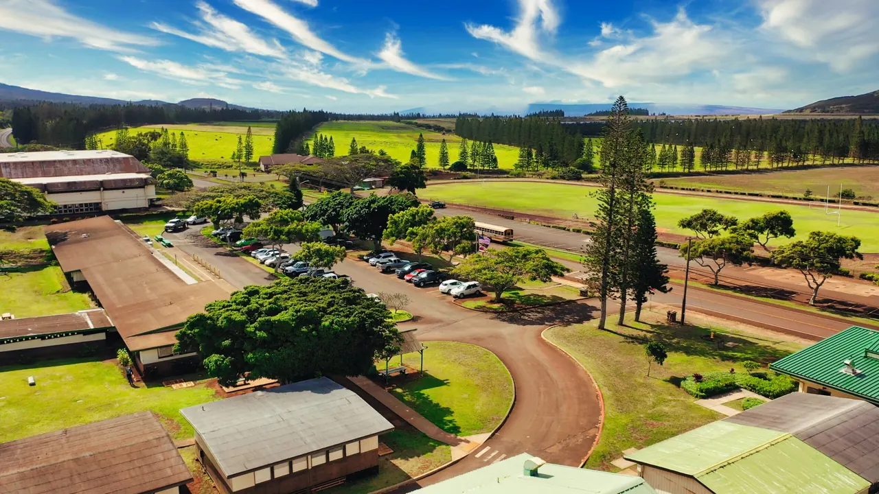 Aerial view of the Molokaʻi High School campus in Hoʻolehua with green fields beyond