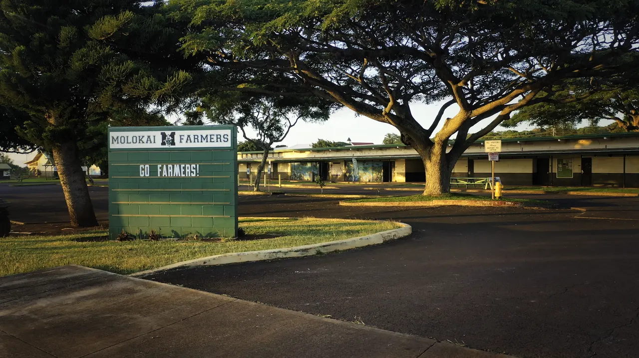 The Molokaʻi High School Farmers sign under the trees at the campus entrance