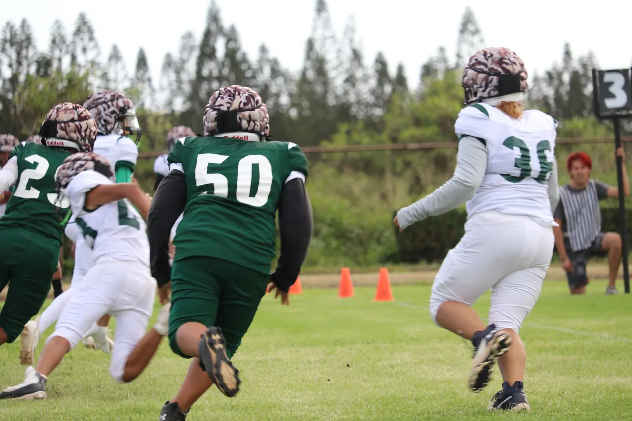 Molokaʻi Farmers football players in green jerseys running a play